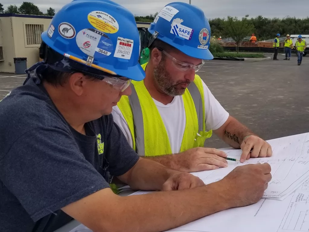 Two men in hardhats looking at plans