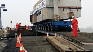 Workers moving a large boiler using a a piece of heavy equipment