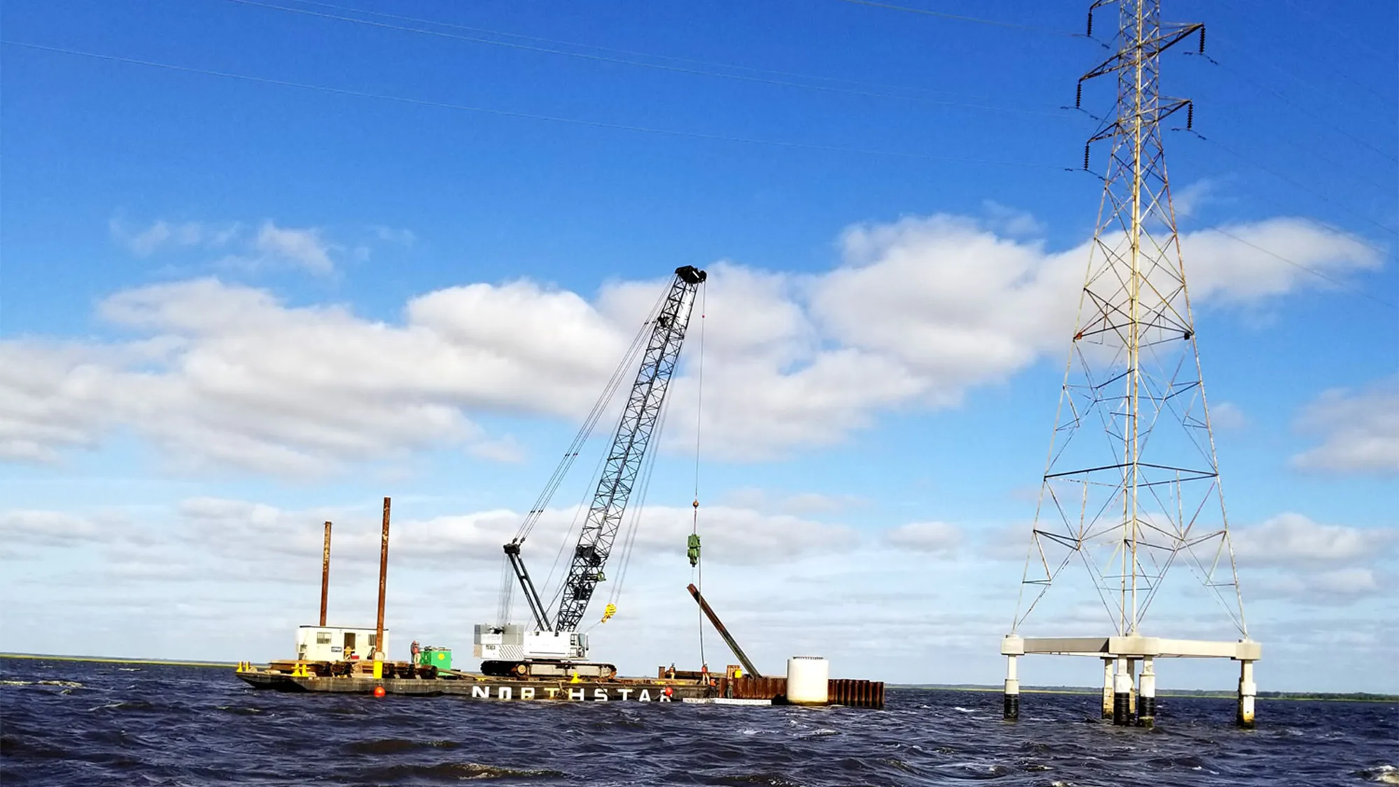 Crane on platform in water lifting a beam