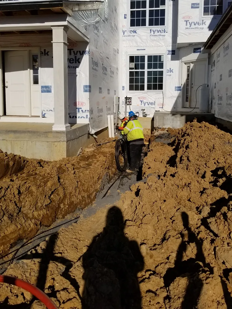 Workers standing in a hole running electrical line