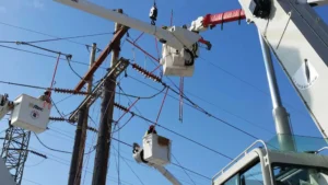 Workers in buckets from a few bucket trucks working on power lines