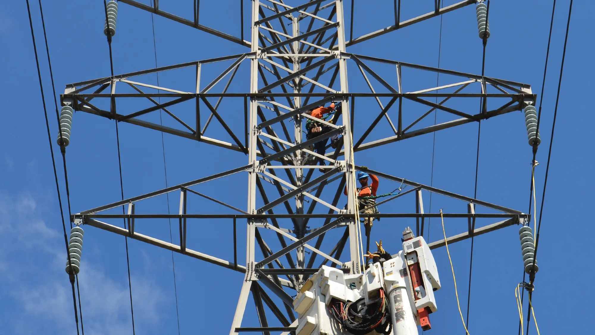 Workers climbing transmission tower