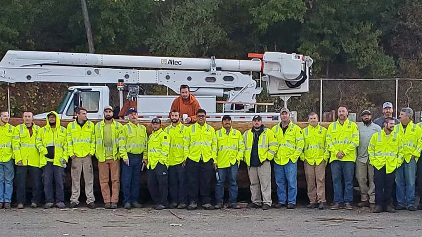 Crew of workers standing in front of bucket truck