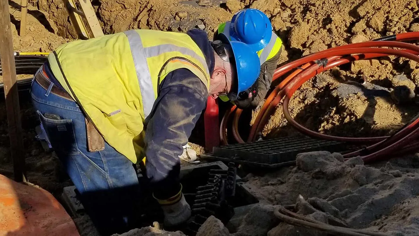 Workers in a hole installing cable